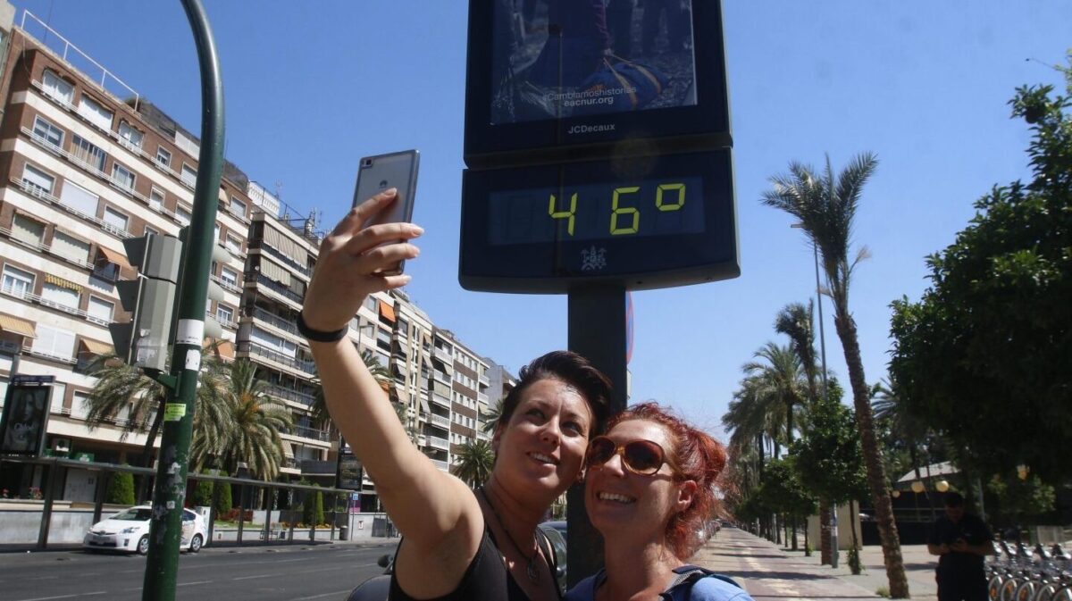 Dos jóvenes se fotografían junto a un termómetro que marca una elevada temperatura.
